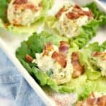 Egg Salad on Lettuce leaves topped with bacon and sitting on a white serving tray