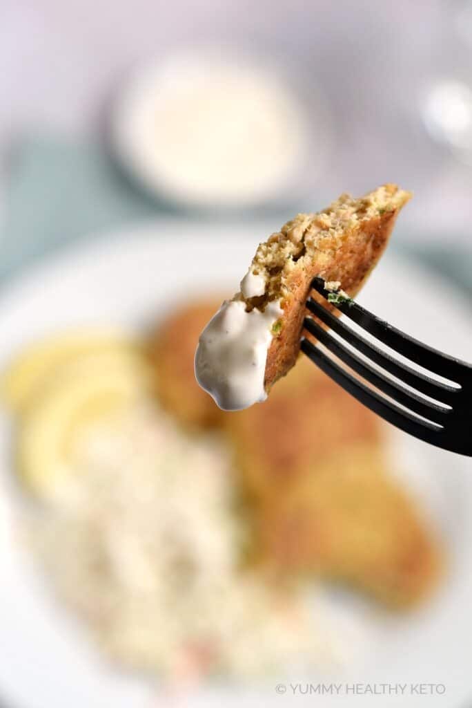 A piece of salmon patty on a fork, dipped in garlic aioli.