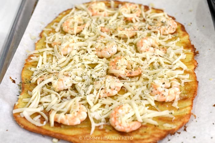 Top the pizza crust with shrimp, shredded cheese and Italian seasoning.