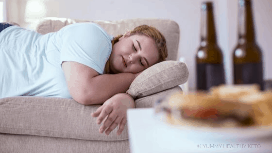 Woman laying on the couch with food on the table.