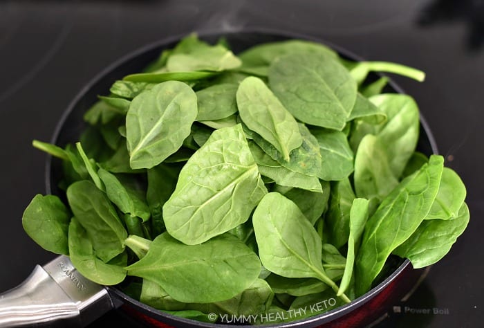 A pile of raw spinach in a small frying pan.