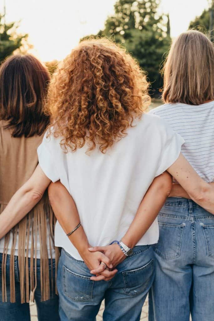 Three women with their arms interlocked behind their backs.